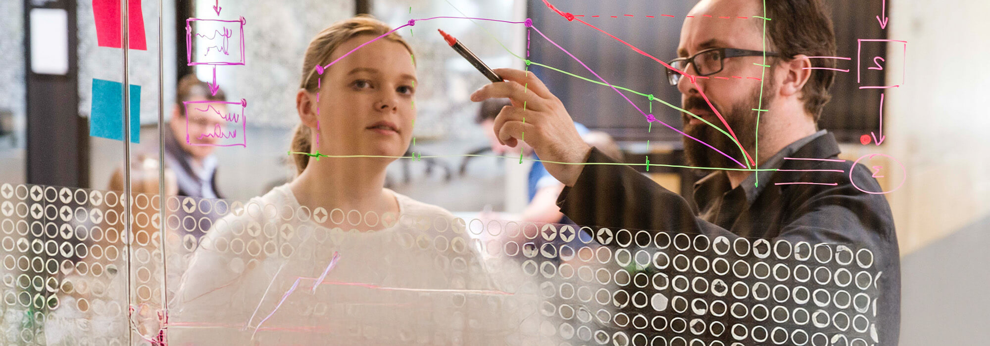 Students discussing sticky notes added to a glass wall