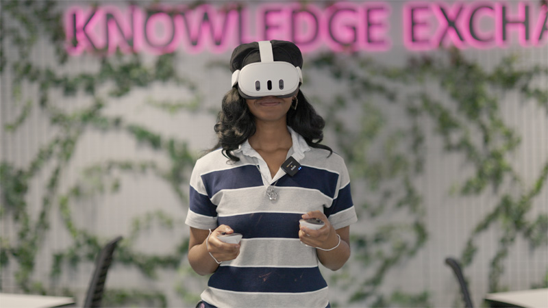 A female wearing a stripey tshirt is wearing a VR headset