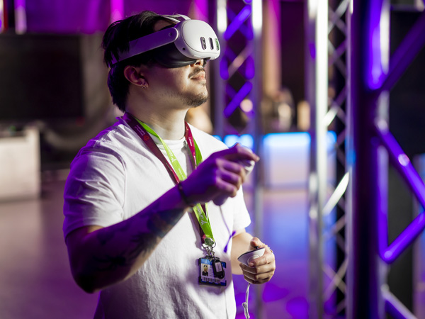 A male is wearing a white VR headset in an ambiently lit gaming studio